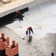 Image from above of men painting waterproofing substance onto commercial roof