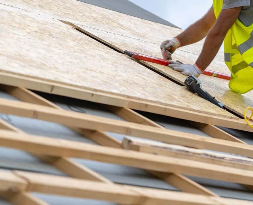 Roofing worker measuring pieces of plywood